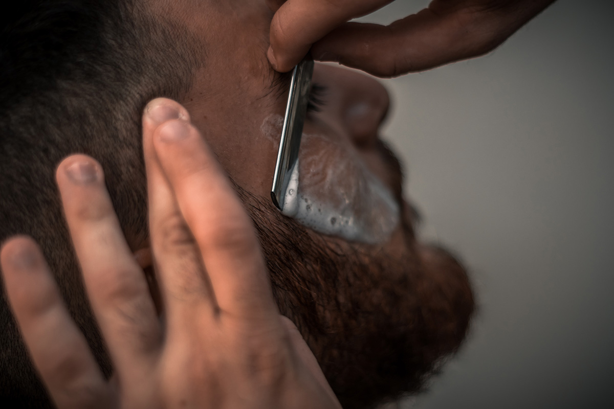 Man having a shave with a straight knife.